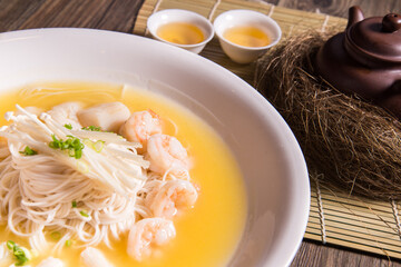 braised thin noodle mee sua with seafood prawn in yellow chicken cheese stock thick gravy sauce in plate on bamboo wood table asian cafe cuisine Chinese restaurant banquet halal food menu