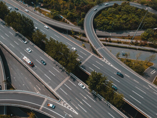 Top up aerial drone view of elevated road and traffic junctions in Chinese metropolis city during sunny day golden hour. Modern construction design of traffic ways to avoid traffic jams. Few vehicles.