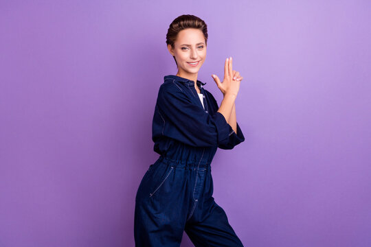 Photo of funny brunette young lady show gun wear jeans overall isolated on violet color background