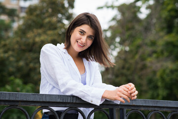 Attractive, happy and stylish brunette Caucasian girl posing on the street. Lifestyle and fashion concept.