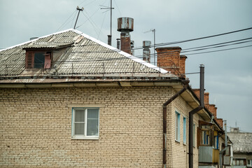 View of the roof of old brick house with chimneys and lots of TV antennas