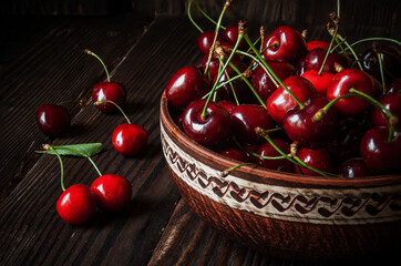 Ripe juicy cherries in a plate on a wooden background