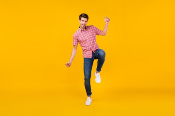 Obraz premium Full body photo of cheerful young happy positive man wear jeans good mood dance isolated on yellow color background