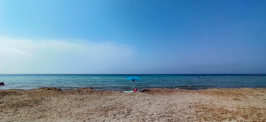 lonely umbrella on empty beach with blue sea. Capo feto, Sicily. Italy