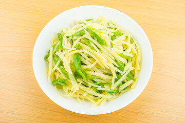 A dish of homemade green pepper and potato shreds on the table