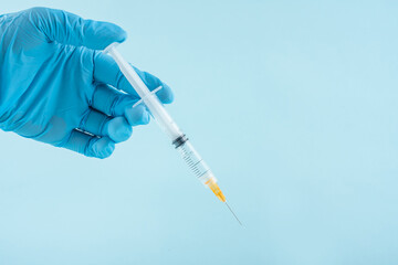 Gloved doctor holding a syringe for injection