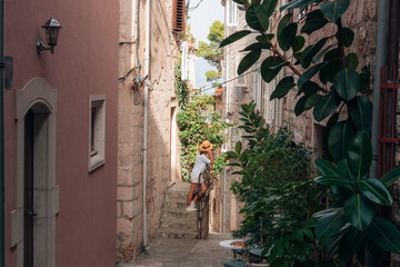 Fototapeta na wymiar Girl tourist walking through ancient narrow street on a beautiful summer day in Korcula, Croatia