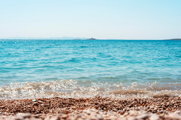 Beautiful pebble beach and blue sea with islands. Shallow depth of field