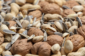 Heap of mixed nuts as background: walnut, peanut, pistachio and sunflower seed. Perspective