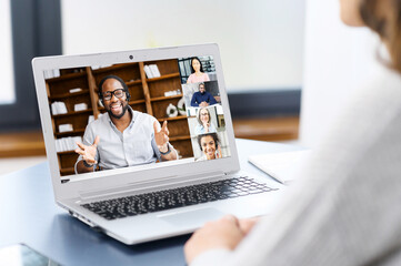Fototapeta na wymiar Female freelancer talking online with group of diverse colleagues or classmates, woman participates in video conference with multiracial team, virtual meeting on the laptop, e-learning