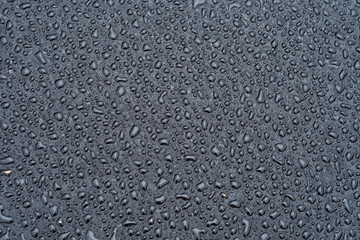 Dark background with large drops of water on fresh asphalt. Road surface wet from rain. Black sad backdrop