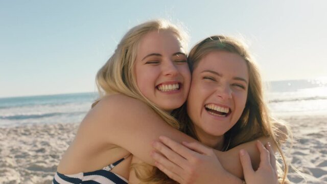 happy woman hugging girl friend on beach giving suprise kiss on cheek best friends having fun summer vacation 