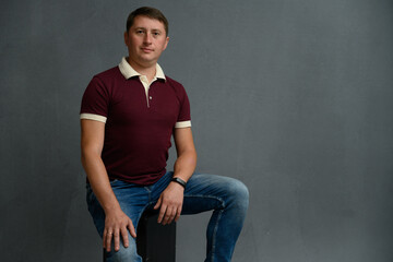 Portrait of a man in the studio sitting on a chair on a gray background