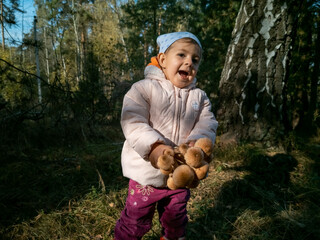 child collecting honey mushrooms in the autumn forest. close-up. toddler holds beautiful edible mushrooms in hands