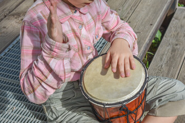 the girl child with a djembe drum outdoor on the porch of the house photo without processing