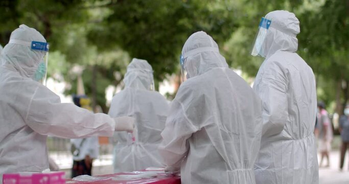 Slow motion of the mobile team of Asian doctors, nurses and staffs wearing PPE, mask, face shield are screening for COVID-19 at high-risk communities using Antigen Test Kid(ATK), nasal secretion swab.