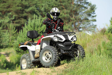 Man driving modern quad bike on sandy road near forest. Extreme sport © New Africa