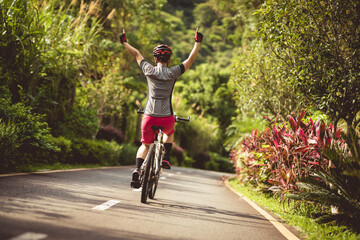 Naklejka premium Woman cycling on tropical park trail in summer