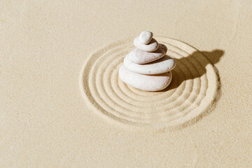 Fototapeta na wymiar Zen garden meditation sandy background with stone cairn and lines on sand. Relaxation balance and harmony