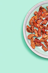 Sun dried tomatoes slices with Italian herbs and spices on blue colored background. Homemade dehydrated vegetable.