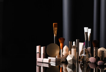 Composition with makeup products on table against black background