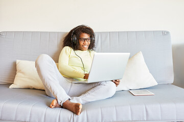 Afrikanische Frau auf dem Sofa zu Hause mit Laptop PC