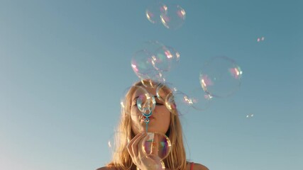 happy young woman blowing bubbles on beach at sunset enjoying summer having fun on vacation by the sea