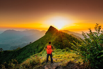 Traveler with backpack from behind and beautiful Landscape of mountain with sunset in Chiang Rai, Thailand