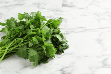 Bunch of fresh aromatic cilantro on white marble table. Space for text