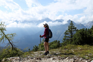 Naklejka premium Beautiful girl wearing sportswear looking at the horizon standing. Sports activity, trekking and hiking in alpine environments.