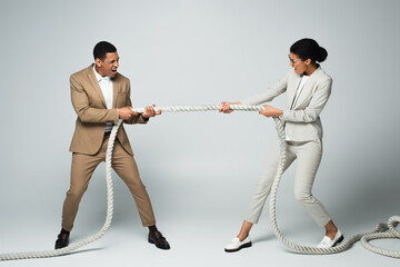 businessman and businesswoman pulling rope on grey, gender equality concept