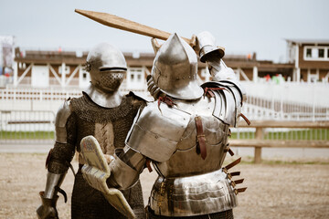Reenactment of the battle of medieval knights in heavy armor on wooden swords