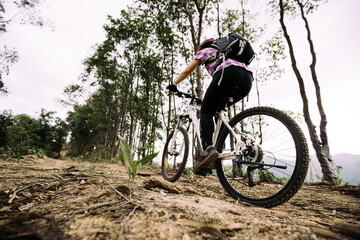Naklejka na ściany i meble Woman cyclist cycling on mountain top forest trail