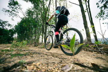 Fototapeta na wymiar Woman cyclist cycling on mountain top forest trail