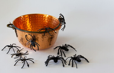 Old cauldron with toy spiders. Halloween background. Selective focus. Copy space.