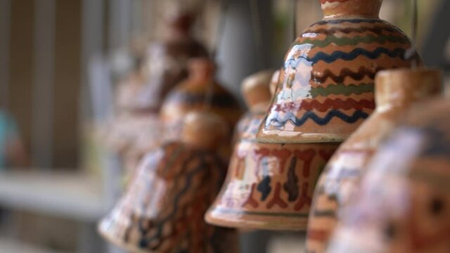 Uzbek bells hanged indoors. Close up of antique Feng shui amulet for luck and protection. Wind swinging clay bells slowly. Feng shui chimes
