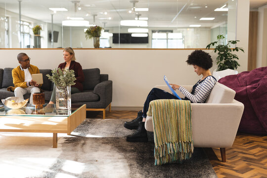 Diverse male and female colleagues working together in workplace lounge area