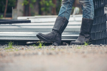 Women wear construction Boots safety footwear for worker at construction site. Woman Engineer Wear Jeans black Boots Worker standing at construction site. Engineer safety industry footwear walking