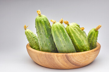 Fresh garden cucumbers in wooden dish bowl isolated on white background