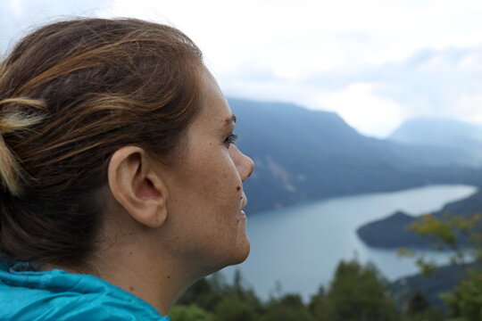 Close-up, beautiful girl looks at the Molveno lake on the horizon from the Pradel plateau in Trentino, Italy.