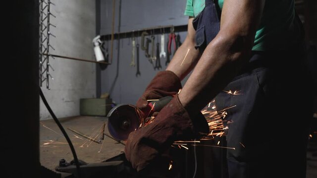 Professional male worker works cutting metal with a grinding machine