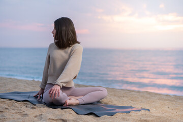 Fototapeta na wymiar Woman doing yoga at the beach at sunrise