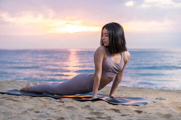 Fototapeta na wymiar Woman doing yoga at the beach at sunrise
