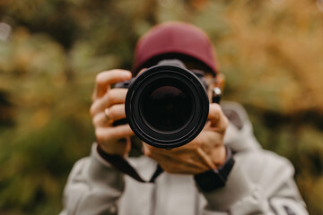 Fototapeta premium stylish bearded photographer with a camera in his hands takes a photo in the autumn park