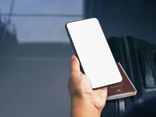 Hand holding of a smartphone with suitcase background. Close-up photo. Space for text. Technology, communication and journey concept