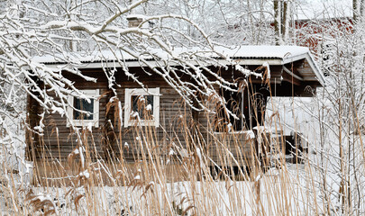 Old log sauna by the lake in winter