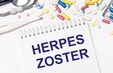 On a light background, multi-colored pills, a stethoscope, an electronic thermometer and a notebook...