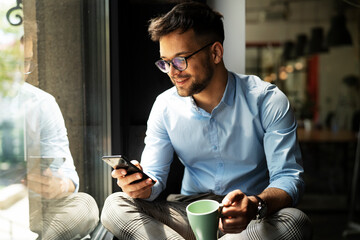 Young businessman drinking coffee in her office. Handsome man on coffee break