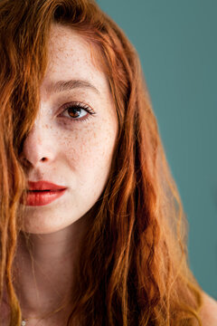 Face of a beautiful woman with red hair and lips isolated on green background
