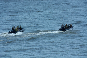 Miltary boats floating on water, armed soldiers of Special Forces aboard